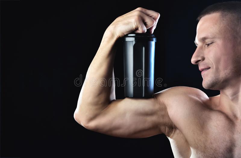 strong muscle man holds biceps black shaker protein strong slim man holds biceps black shaker protein guy 136067146